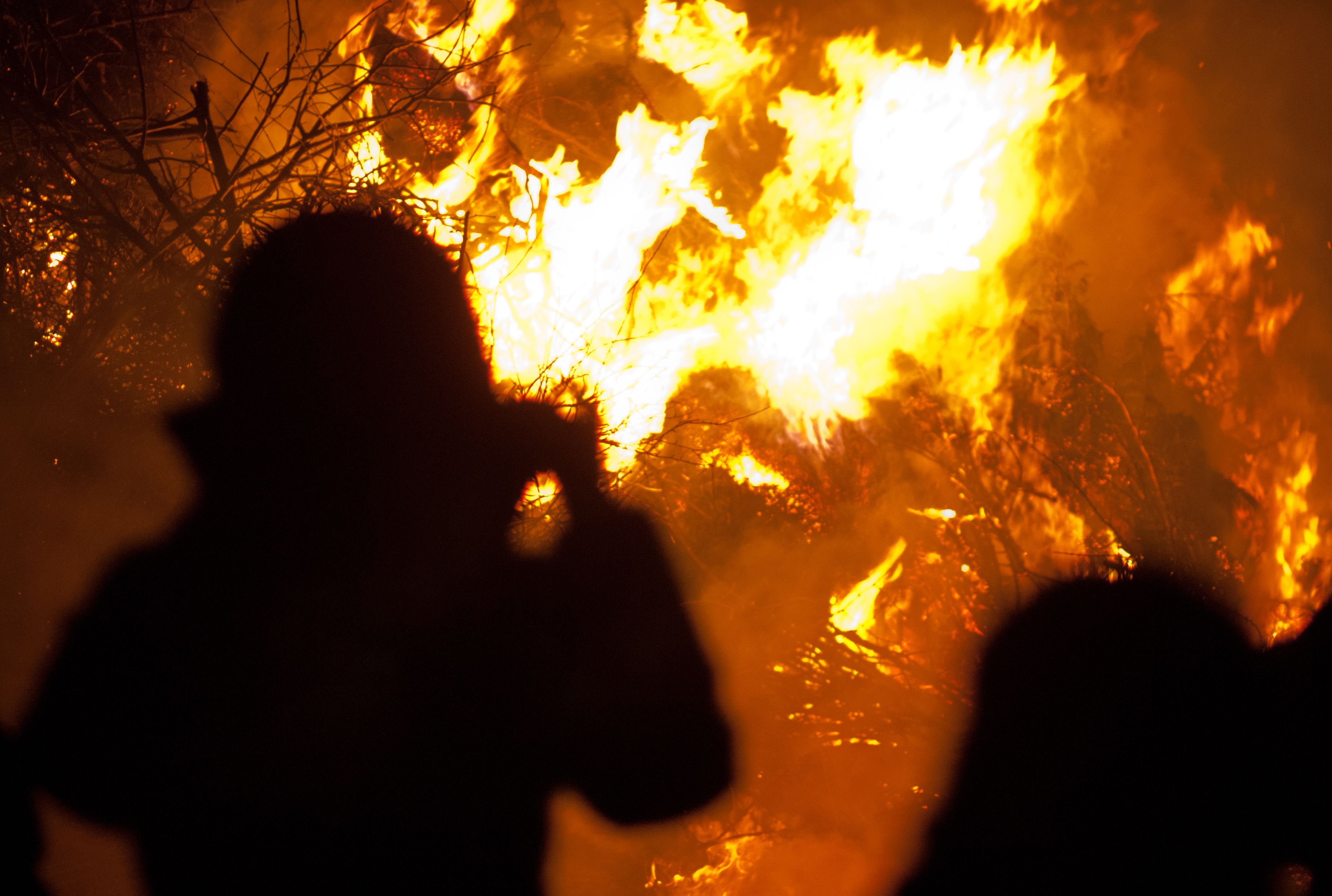 Silhouette einer Person vor einem großem Feuerhaufen