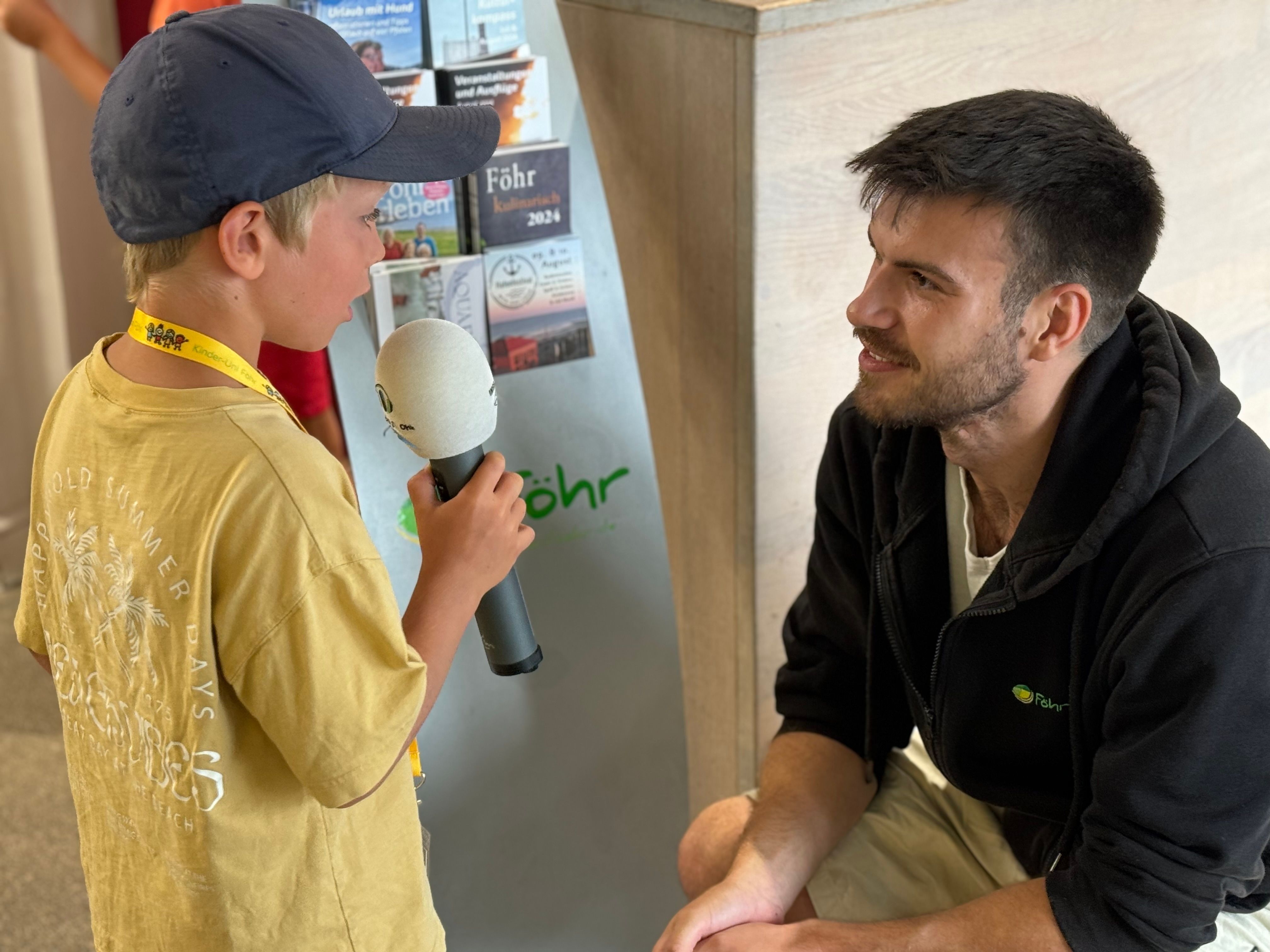 Ein kleiner Kinder-Uni-Reporter interviewt Kinder-Uni-Organisator Zag Below von der FTG