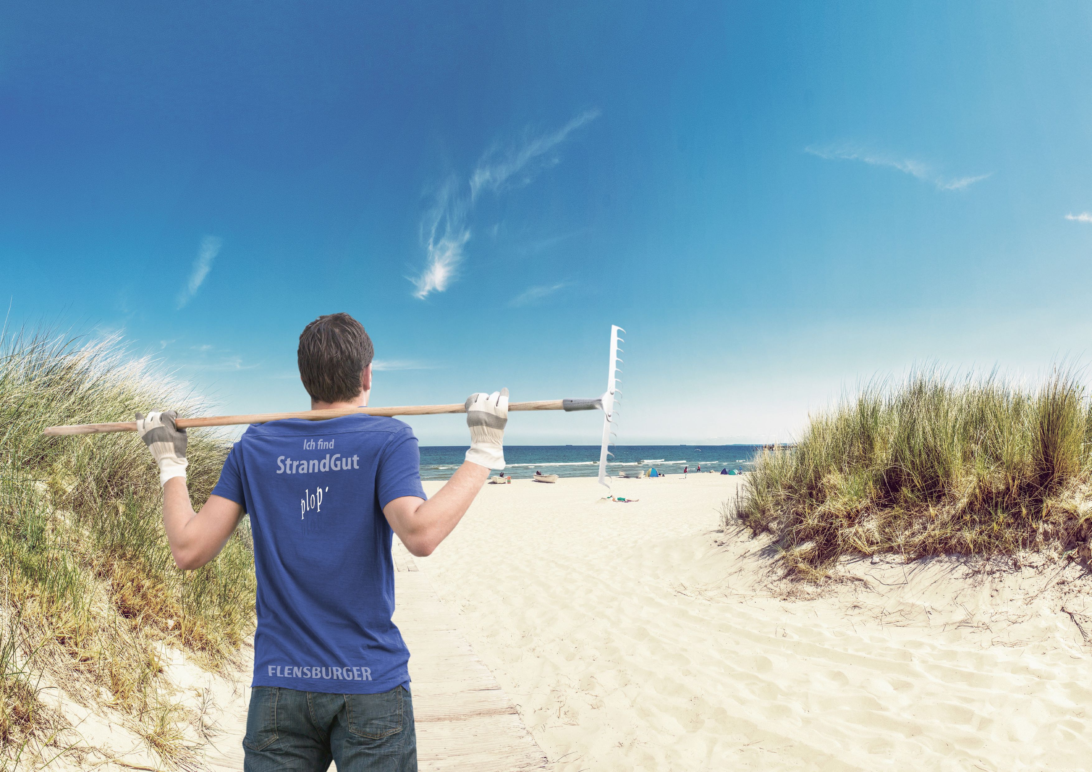 Person am Strand mit einer Harke zum Aufsammeln von Müll