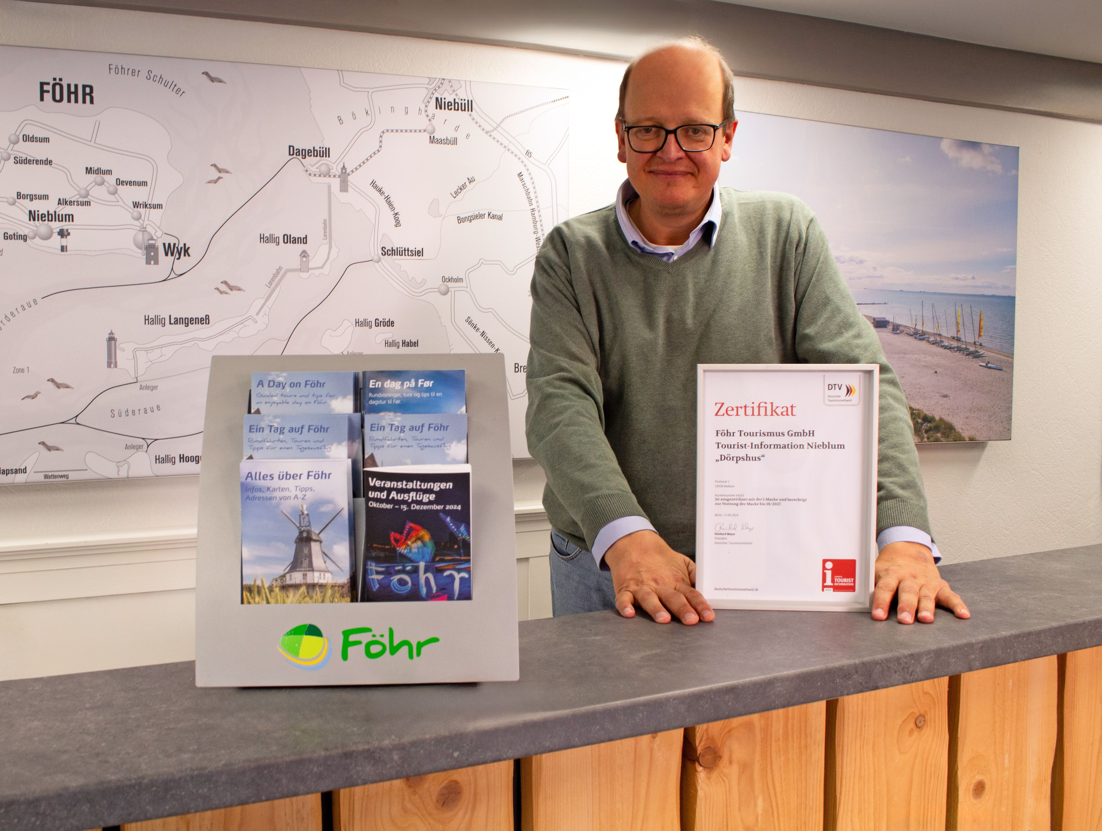 FTG-Mitarbeiter Ralf Brodersen hält das Zertifikat der i-Marke in der Hand